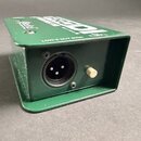 Zelený kovový box s nápisem LOW-Z OUT 600Ω. Na zadní straně je umístěn jeden trojpólový XLR konektor a malý bílý knoflík. Na horní části je viditelné…