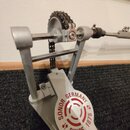 Stříbrný kovový mechanismus basového pedálu s řetězem. Na spodní části je červený kulatý nápis SONOR GERMANY SINCE 1875. Povrch vykazuje mírné známky…