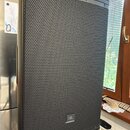Černý aktivní reproduktor s kovovou mřížkou v horní a spodní části. V dolní části mřížky je umístěno logo JBL. Povrch přístroje i mřížka vykazují zná…