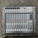 Stříbrný mixážní pult s černým rámem a mnoha potenciometry, posuvníky a konektory. V pravém horním rohu je nápis EURORACK MX 2004 a pod ním text 16-C…