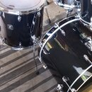 Černá bicí souprava s chromovaným kováním. Na tomare na levé straně je viditelné logo "Ludwig" a nápis "Black Beauty". Souprava obsahuje basové buben…