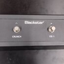 Černý obdélníkový nožní spínač s čtyřmi kovovými tlačítky. Uprostřed horní části je bílý nápis Blackstar. Pod tlačítky jsou zleva doprava bílé popisk…