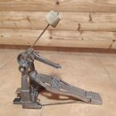 Kovový basový pedál s bílým plstěným beaterem. Na stupni je vyražen nápis TAMA IRON COBRA. Povrch kovu vykazuje známky běžného používání a mírné zmat…