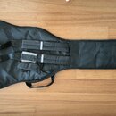 Černý softcase na kytaru s ramenními popruhy a úchytem. Na horním konci je bílé logo ve tvaru štítu s písmeny „H“ a „B“. Povrch materiálu vykazuje mí…