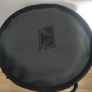 Kruhová černá podložka nebo pouzdro z syntetického materiálu. Uprostřed je vyražené logo ve tvaru stylizovaného písmene T v rámečku. Povrch vykazuje…