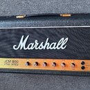 Kytarový zesilovač v černém vinylovém potahu s bílým logem Marshall na předním textilním krytu. Na zlatém ovládacím panelu je nápis JCM 800 LEAD SERI…