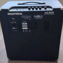 Černý basový kombozesilovač s kovovými rohy a úchytem na horní straně. Na zadním panelu je bílý nápis Hartke a označení modelu HD 500 500W BASS AMPLI…