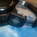 Detail černé studiové sluchátka s nápisem STUDIO HEADPHONE a logem NEUMANN BERLIN. Na bočním plastovém krytu je bílé kosočtvrné logo s nápisem ZZRC M…