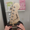 Fotografie zachycuje hlavu elektrické kytary z přírodního světlého dřeva. Na hlavě je černý nápis Squier MINI by Fender. Nástroj má šest chromovaných…
