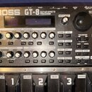 Černý kytarový procesor Boss GT-8 Guitar Effects Processor. Zařízení obsahuje displej, početné otočné knoflíky a tlačítka s nápisy jako PREAMP/SPEAKE…