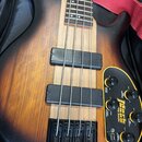 Elektrická basová kytara s tělem v černé a hnědé barvě (sunburst) a světle barevným středovým pruhem z dřeva. Na těle jsou dva černé snímače a čtyři…