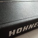 Detailní pohled na černý obal z texturovaného materiálu. Na boční straně je bílým nápisem vyšívane logo HOHNER. Povrch materiálu je v dobrém stavu be…
