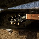Černá kytara v černém pouzdře. Na hlavě nástroje je zlatý nápis Gibson. Hřebeníky jsou bílé a ladicí mechanismy chromované.