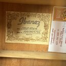 Fotografie zachycuje vnitřek akustického nástroje s dvěma nalepenými štítky. První štítek nese logo Ibanez a texty MODEL No. V50JP-NT-27-02, SERIAL N…