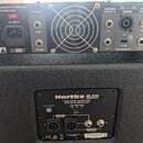 Zadní strana basového zesilovače Hartke LH1000 a reproduktorové skříně Hartke HL210. Zesilovač má stříbrný povrch, ventilátor vprostřed a nápisy SPEA…