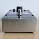 Kytarový efekt v kovovém šasi stříbrné barvy s broušeným povrchem. Na horní straně je fialový panel s nápisem ELECTRO HARMONIX a částečně viditelným…