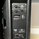 Zadní panel černého aktivního reproduktoru. Na panelu jsou nápisy OPERA 12 a dbTechnologies DESIGNED & DEVELOPED IN ITALY. Horní část obsahuje vstupy…