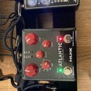 Tři efektové pedály umístěné na černém pedalboardu. Horní pedál je černý s bílými nápisy „HEAVYHAND“ a „K-Drive“, má čtyři průhledné knofíky a jeden…