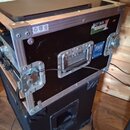 Černý transportní case s hliníkovými hranami a rohy. Na přední straně je nápis „DUCT TAPE“ na nálepce a modré logo s textem „THT CASE“ a webovou adre…