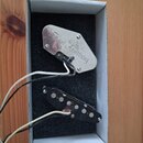 V bílé krabici s černou pěnovou vložkou jsou dva elektrické snímače s připojenými kabely. Horní snímač má kovový kryt s nápisem Kent Armstrong. Dolní…
