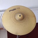 Zlatý kovový činel umístěný na stojanu. Na povrchu je černý nápis PAiSte 302 a pod ním menší text 20" Ride. Povrch činelu vykazuje drobné škrábance a…