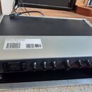 Digitální procesor v hliníkovém přepravním kufru. Na přístroji je bílá nálepka s nápisem M300 Dual Engine Processor a Serial Number 5622407. Přední p…