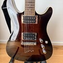 Elektrická kytara s tmavě hnědým průhledným lakem, která odhaluje strukturu dřeva. Má dva humbuckery, přičemž na spodním snímači je nápis Seymour Dun…