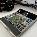 Bílo-šedý samplér s černými ovládacími prvky a gumovou podložkou. Na horní straně je červené logo AKAI a nápis MPC SAMPLE, stejný nápis je vyryt i na…