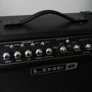 Černý kytarový kombo zesilovač značky LINE 6. Na ovládacím panelu je nápis SPIDER IV 15 a přepínače AMP MODELS s označením CLEAN, CRUNCH, METAL, INSA…