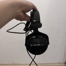 Černé uzavřené sluchátka s kabelem. Na vnější straně mušle je bílý nápis DT 770 PRO 80 OHM a na hlavovém oblouku je viditelné logo beyerdynamic. Povr…