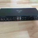 Zadní strana černého audio rozhraní s nápisem U-PHORIA UMC404HD. Na horní straně je logo a nápis behringer (zrcákově). Zařízení obsahuje různé konekt…