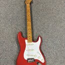 Červená elektrická kytara s bílým pickguardem a hnedým javorovým hřidlem. Na hlavě je viditelné logo Squier. Kytara má tři snímače, pětipositionní př…