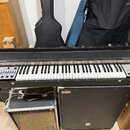 Černý klávesový nástroj s bílými a černými klávesami. Na levé straně je nápis HOHNER a na pravé straně nápis String Performer. V levé části se nacház…