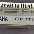 Stříbrný klavír s nápisy YAMAHA a MOTIF6. Na levé straně je viditelné logo Yamaha v kruhu. Povrch nástroje vykazuje drobné škrábance a opotřebení, ze…