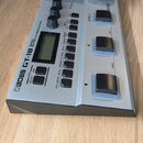 Stříbrný basový efektový procesor s černými ovládacími prvky a černým pedálem. Na přístroji je nápis BOSS GT-1B BASS EFFECTS PROCESSOR a v pravém hor…
