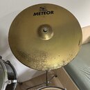 Zlatý činely s koncentrickými drážkami. Na povrchu je černý nápis METEOR a nad ním logo s textem MEINL. V dolní části činely vykazuje viditelné opotř…