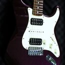 Elektrická kytara s tmavě fialovým metalizovaným povrchem těla a bílým pickguardem. Nástroj má konfiguraci snímačů humbucker-single-humbucker a tři b…