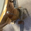 Detailní pohled na basový buben v žlutohnědé barvě s kovovým pedálem. Na povrchu korpusu jsou vidět drobné škrábance a známky opotřebení. Na fotce ne…