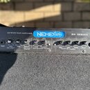 Černý basový zesilovač s nápisy 320 WATT BASS AMPLIFIER, NEMESIS a RS SERIES. Panel obsahuje ovládací knoflíky s popisky Input, Gain (Pull- 12 dB pad…