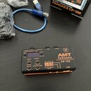 Černý kompaktní efekt pedál s oranžovým spodním okrajem. Na horní straně je nápis AMT PANGAEA IR CONVOLUTION PLAYER CP-100, malý displej a ovládací t…