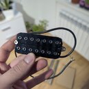 Černý humbucker s dvěma řadami šesti viditelných snímacích pólů. Snímač má připojovací kabel a kovové montážní úchyty po stranách. Povrch plastového…