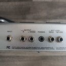 Detailní pohled na stříbrný panel s konektory. Jsou zde nápisy INPUT, OUTPUT R L/MONO, PHONES a EXT LOOP SEND RETURN. V levé části je vidět logo FC a…
