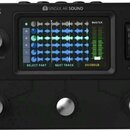 Černý loop studio přístroj s nápisy AEROS a SINGULAR SOUND. Zařízení má pět kovových tlačítek, displej zobrazující modré zvukové vlny a zelený indiká…
