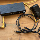 Černý obdélníkový přístroj s nápisem Moog na horní straně. Na přední straně jsou čtyři USB porty a pět jackových vstupů/výstupů. K přístroji jsou při…