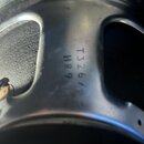 Detail stříbrného kovového rámu reproduktoru. Na povrchu je vyražen nápis T326/B a pod ním HR9. Povrch vykazuje mírné znečištění a drobné škrábance.