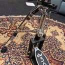 Kromě části stojanu je na fotografii vidět černý basový pedál s chromovanými mechanismy. Na šlapáku je bílým nápisem značka a model dw 5000. Na černé…