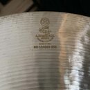 Detail stříbrného kovového činele s viditelným rýhováním povrchu. Na povrchu je vyražen nápis K Istanbul & Co, TURKISH CYMBALS, GENUINE, MADE IN USA…