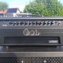 Černý kytarový zesilovač s nápisem Paul Reed Smith na předním panelu. V pravém dolním rohu je štítek s textem ARCHON 50 CLASSIC. Horní ovládací panel…