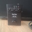 Černý kytarový výkonový zesilovač s nápisy „Harley Benton“, „GPA-100“ a „Guitar Power Amplifier“. Na horní části jsou tři ovládací knoflíky s popisky…