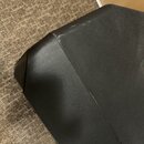 Detailní pohled na horní hranu a roh černého hudebního zesilovače nebo reproduktoru s povrchem z textury imitující kůži. Na hraně jsou viditelné svět…